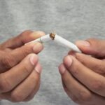 Person breaking a cigarette in half, symbolizing quitting smoking for better health.